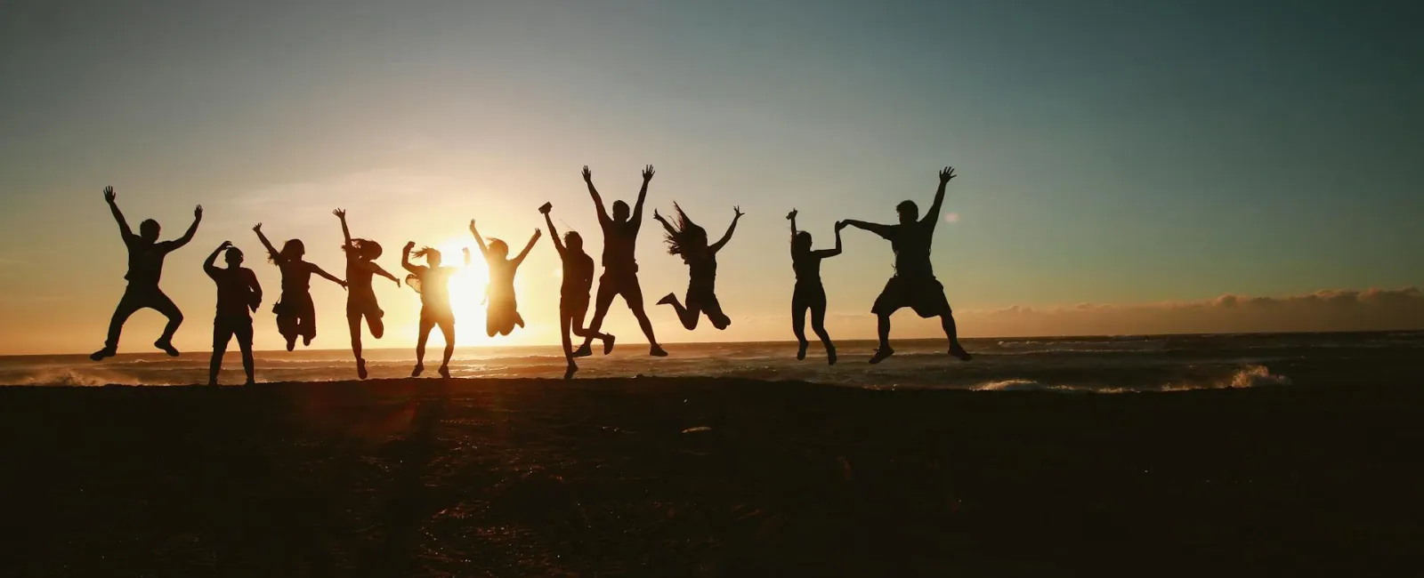 people jumping on a beach in sunset